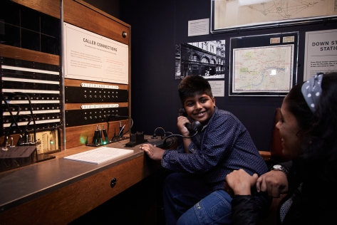 A child and his mother pretend to use a phone exchange from the 1940s