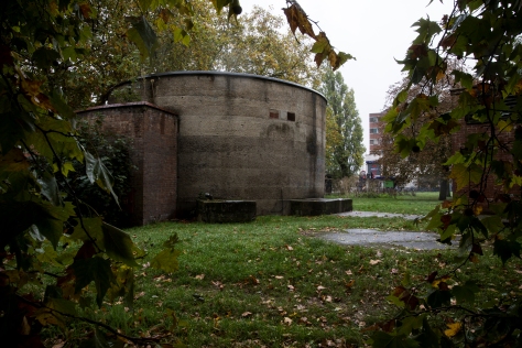 A circular concrete building in the middle of a green area