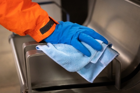 Close-up of gloved hand cleaning a metal seat
